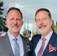 two men in suits posing for a photo