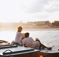 two people sitting on a boat in front of the ocean