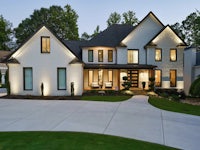 a beautiful home with a driveway and lighting